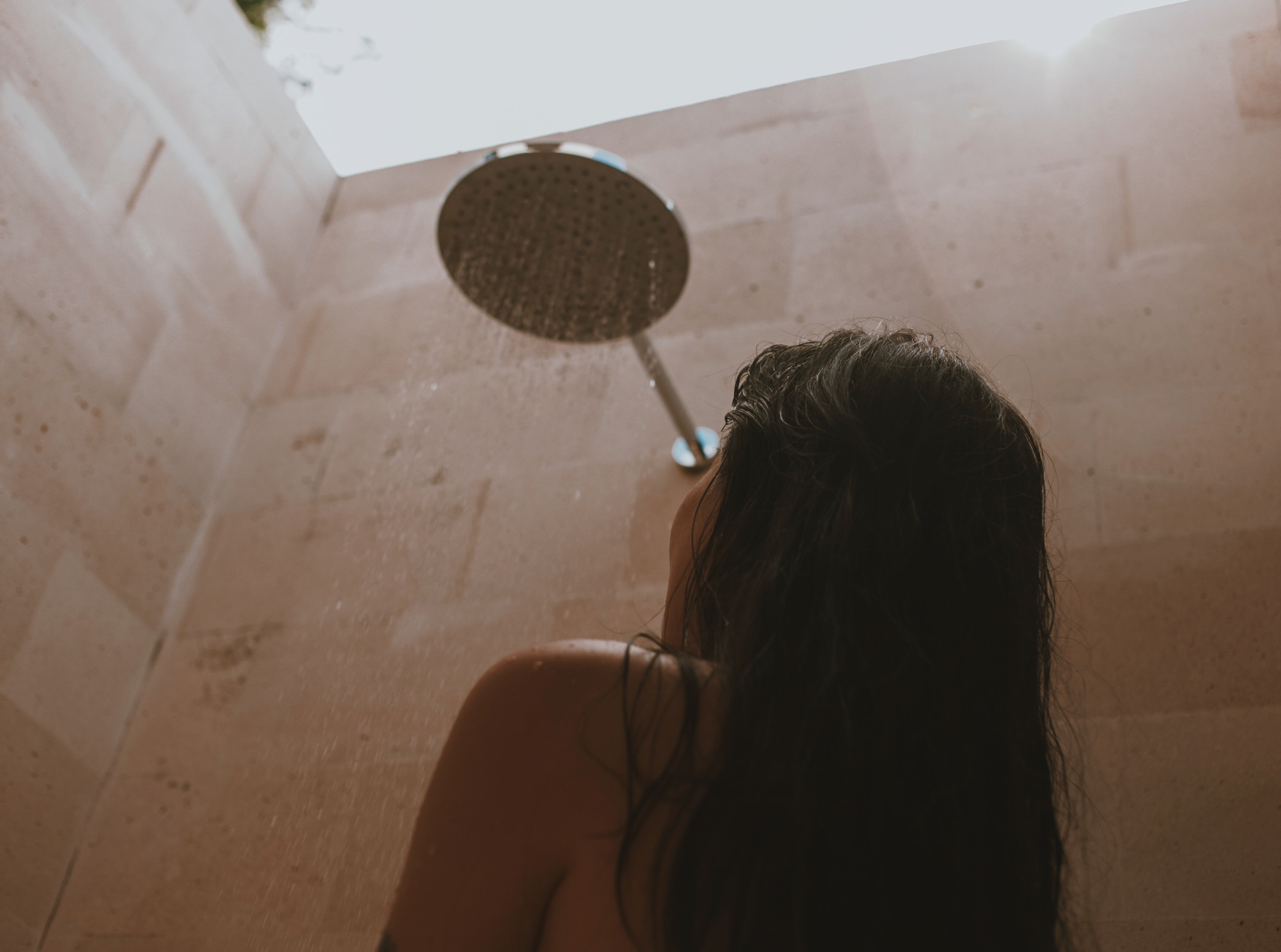 Rear view of woman with dark long hair in shower